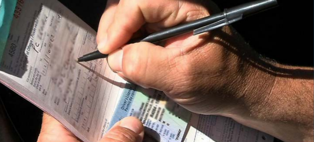 A police officer's hand writing a ticket for an offence in Ontario.