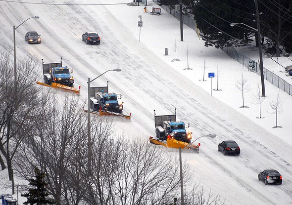 A stock photo showing snow plows plowing a road covered in snow