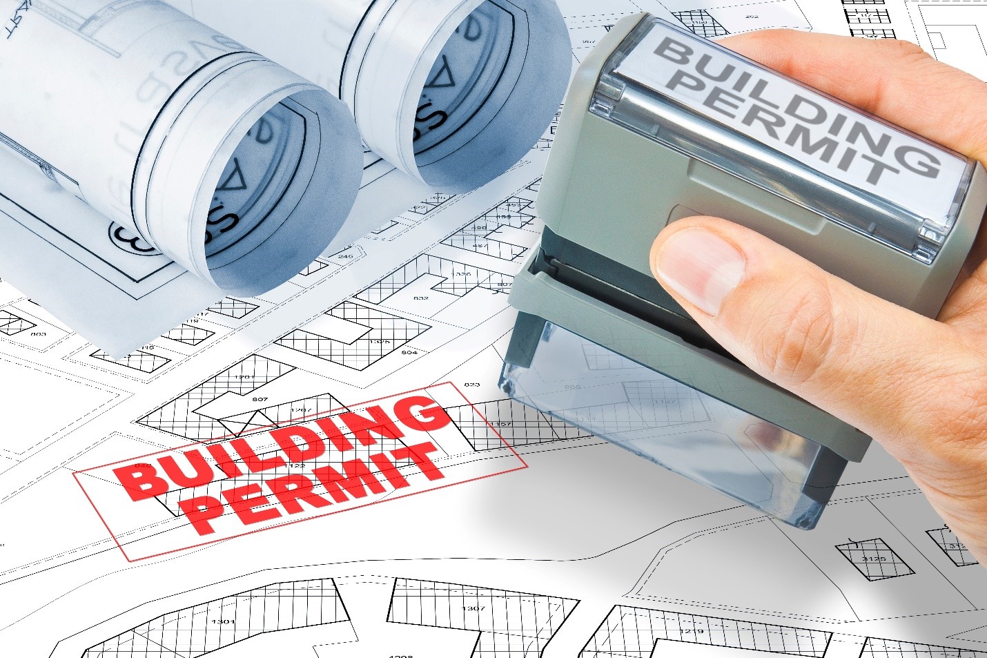 A hand holding a building permit stamp Description automatically generated